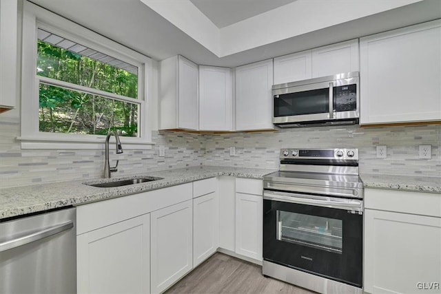 kitchen featuring light stone countertops, appliances with stainless steel finishes, sink, and white cabinets