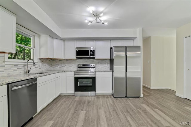 kitchen featuring light stone countertops, stainless steel appliances, sink, and white cabinets