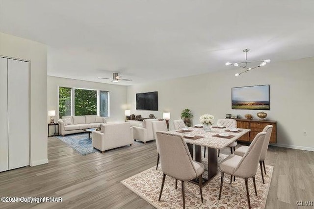 dining room featuring ceiling fan with notable chandelier and light wood-type flooring