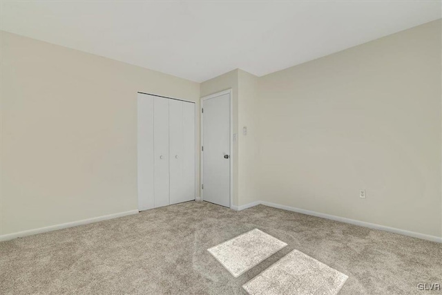 unfurnished bedroom with light colored carpet and a closet