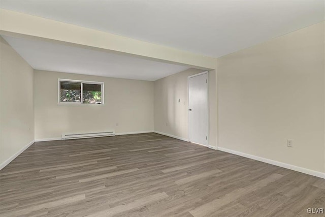 empty room with wood-type flooring and baseboard heating