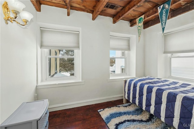 bedroom featuring beamed ceiling, dark wood-type flooring, multiple windows, and wooden ceiling