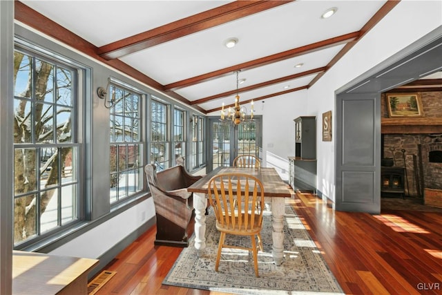 dining space featuring a notable chandelier, dark wood-type flooring, a wealth of natural light, and vaulted ceiling with beams