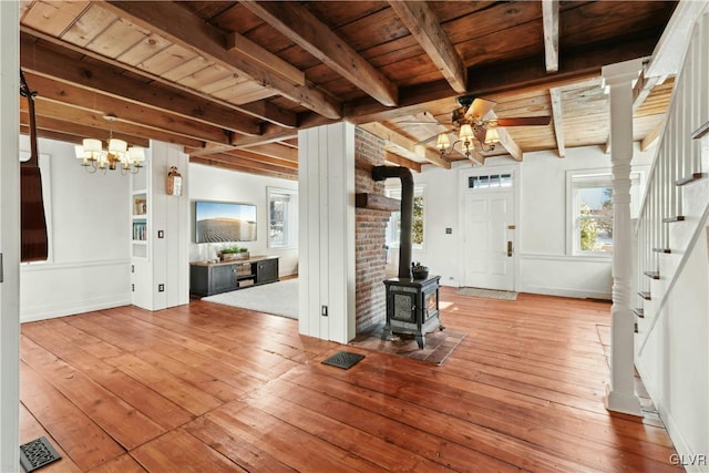 interior space featuring wood ceiling, ceiling fan, wood-type flooring, beamed ceiling, and a wood stove