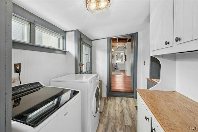 laundry area featuring cabinets, washing machine and clothes dryer, and light hardwood / wood-style flooring