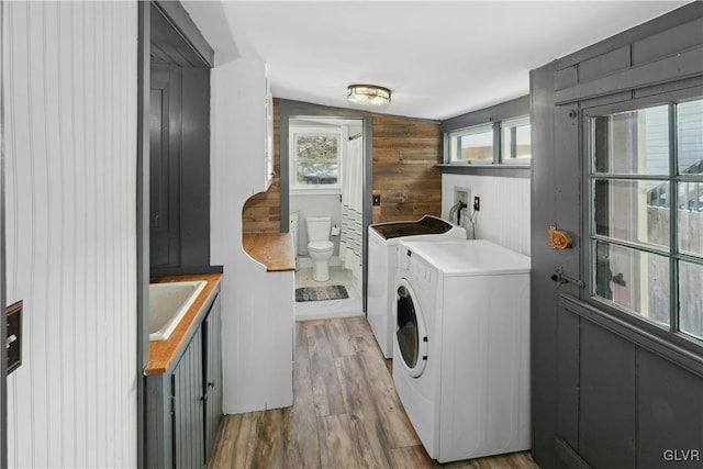 clothes washing area featuring sink, a wealth of natural light, washing machine and dryer, and wood-type flooring