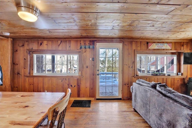 dining room featuring wood walls, light hardwood / wood-style flooring, and wooden ceiling