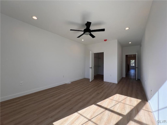 unfurnished bedroom featuring a walk in closet, dark hardwood / wood-style floors, ceiling fan, and a closet