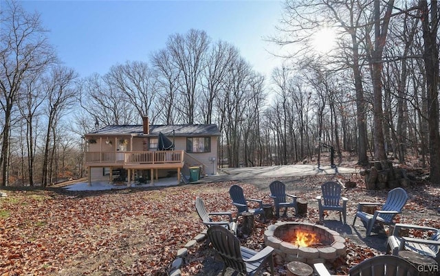 rear view of property featuring a wooden deck, a fire pit, and a patio area