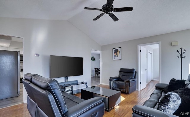 living room with lofted ceiling, ceiling fan, and light wood-type flooring