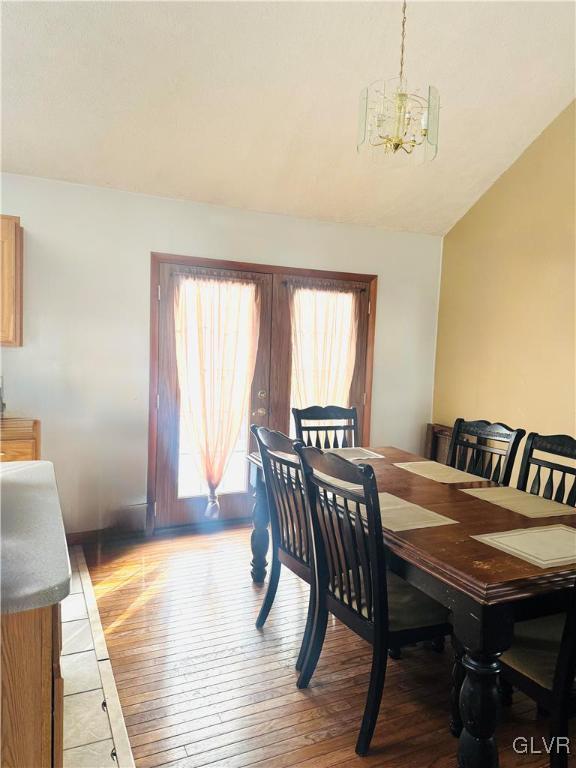 dining room with a chandelier, light wood finished floors, and vaulted ceiling
