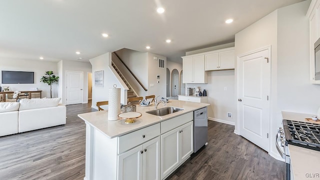 kitchen with sink, white cabinetry, appliances with stainless steel finishes, dark hardwood / wood-style flooring, and a kitchen island with sink