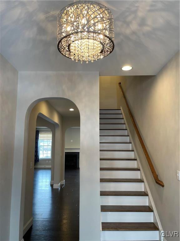 staircase featuring wood-type flooring and a chandelier