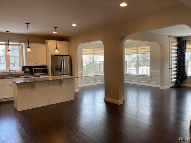 kitchen with stone counters, a center island, appliances with stainless steel finishes, and sink