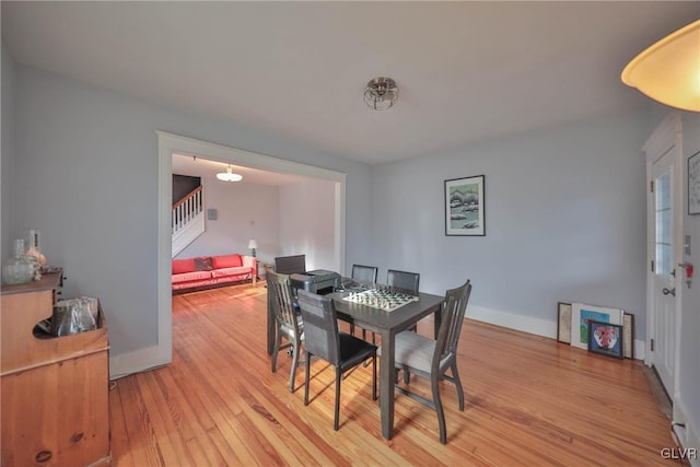 dining room with light wood-style flooring, stairs, and baseboards