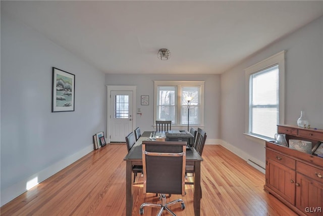 dining space featuring baseboard heating, light wood-style flooring, and baseboards