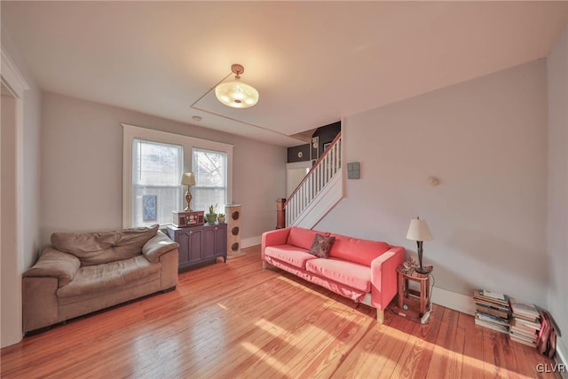 living room featuring light wood-style floors, stairway, and baseboards