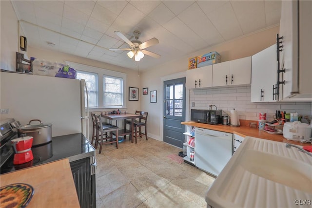 kitchen with white appliances, tasteful backsplash, white cabinets, and ceiling fan