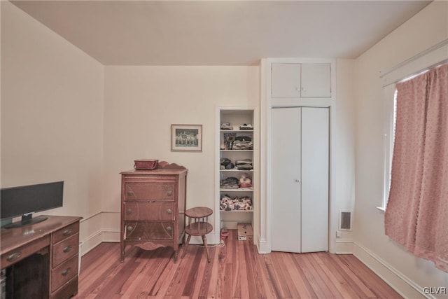 office area with light wood-type flooring, visible vents, and baseboards