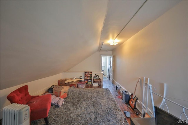 playroom featuring lofted ceiling, baseboards, radiator heating unit, and wood finished floors