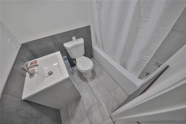 bathroom with toilet, vanity, tile walls, tile patterned floors, and shower / bath combo