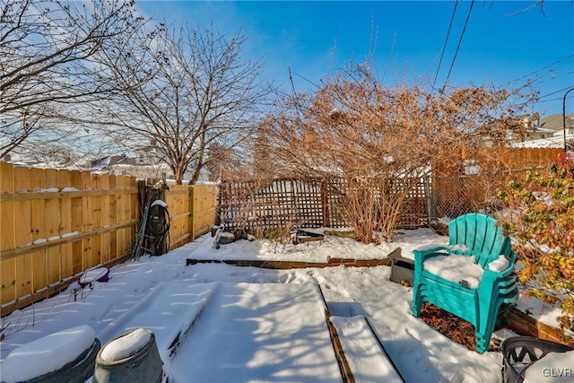 snow covered patio with a fenced backyard