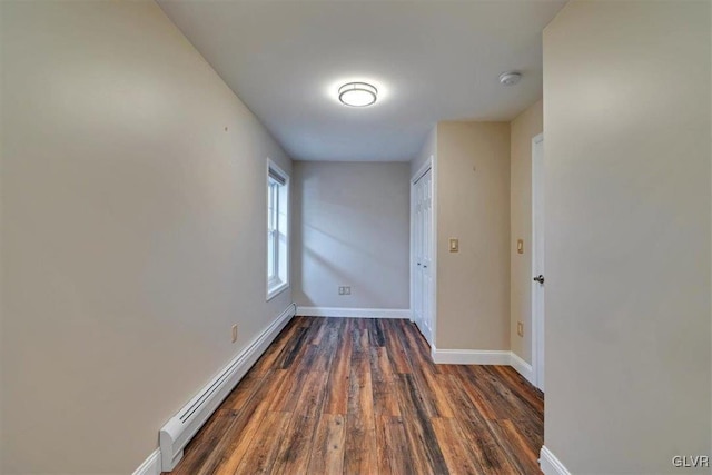 corridor with dark hardwood / wood-style flooring and a baseboard heating unit