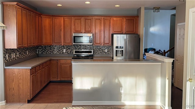 kitchen featuring stainless steel appliances, light tile patterned flooring, and backsplash