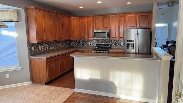 kitchen with light tile patterned flooring, stainless steel appliances, a kitchen island, and decorative backsplash