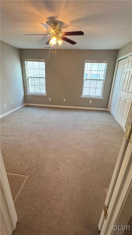 carpeted spare room featuring ceiling fan and a textured ceiling