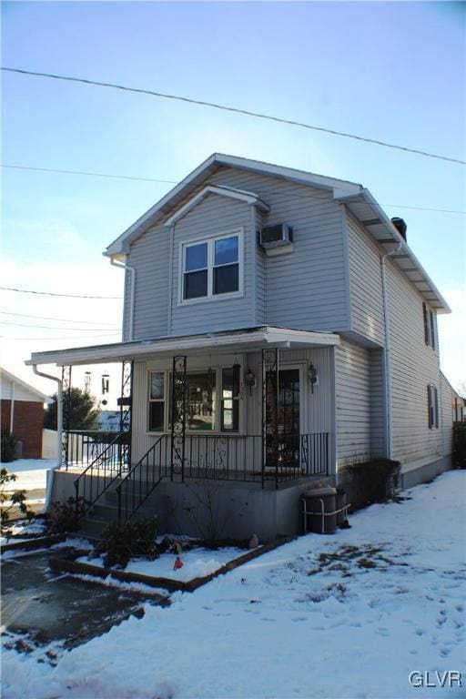 view of front of house with a porch and a wall unit AC