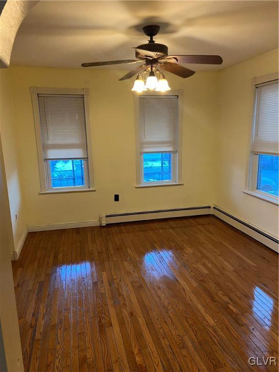 spare room featuring hardwood / wood-style floors, ceiling fan, and baseboard heating