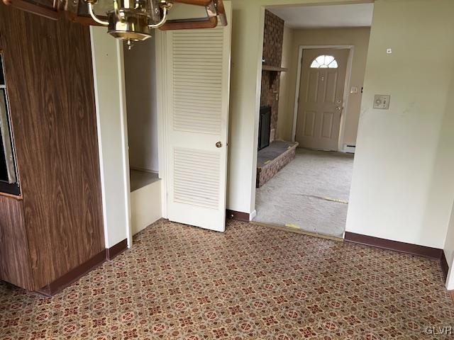 interior space with an inviting chandelier, carpet flooring, baseboard heating, and a brick fireplace