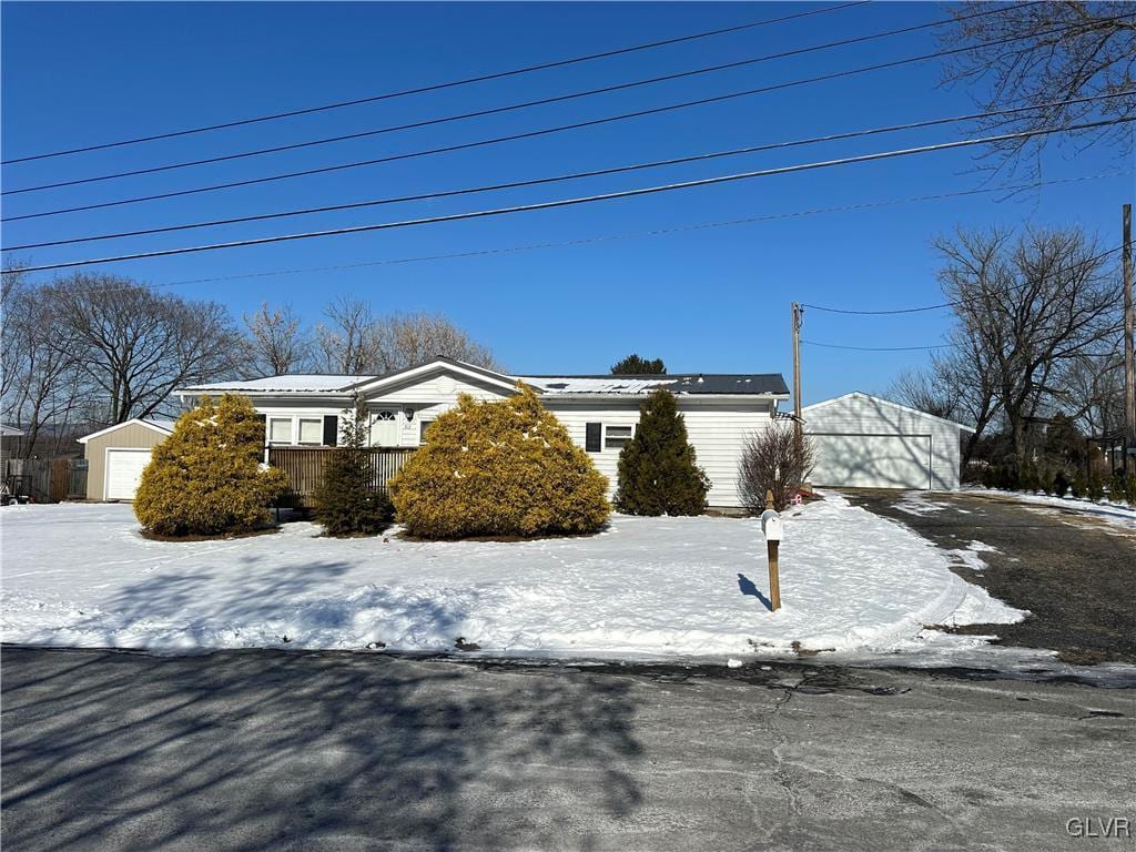 snow covered property featuring a garage and an outdoor structure