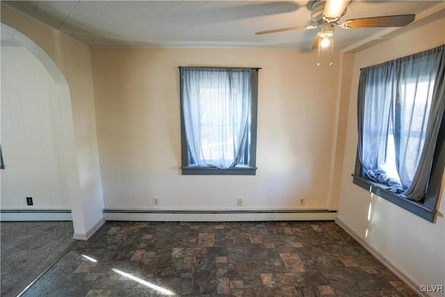 carpeted spare room featuring a baseboard heating unit, a wealth of natural light, and ceiling fan