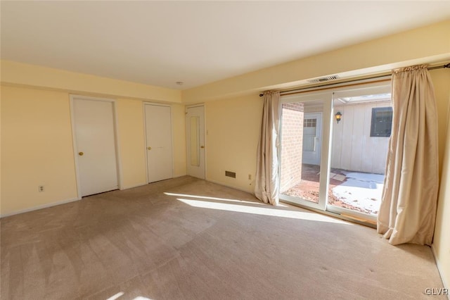 unfurnished bedroom with two closets, light carpet, and access to outside