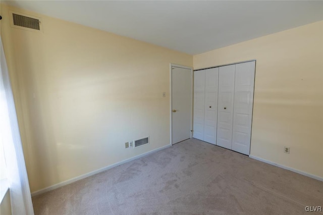 unfurnished bedroom with light colored carpet and a closet