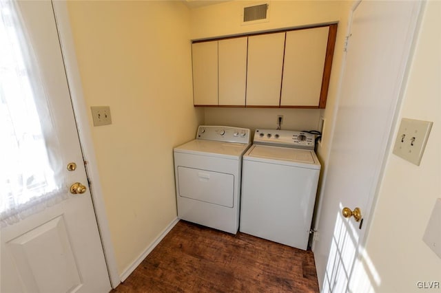 clothes washing area featuring dark hardwood / wood-style flooring, cabinets, and washing machine and clothes dryer