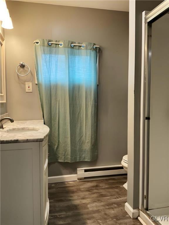 full bathroom with toilet, a shower with door, wood finished floors, baseboard heating, and vanity