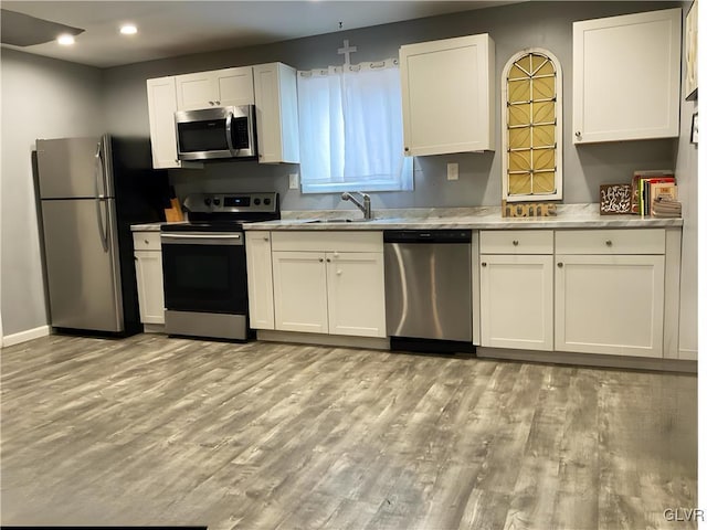 kitchen with stainless steel appliances, recessed lighting, light wood-style flooring, white cabinets, and a sink