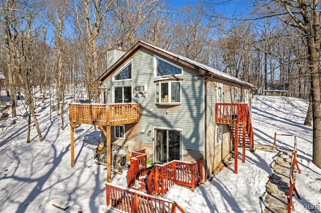 snow covered rear of property with a wooden deck