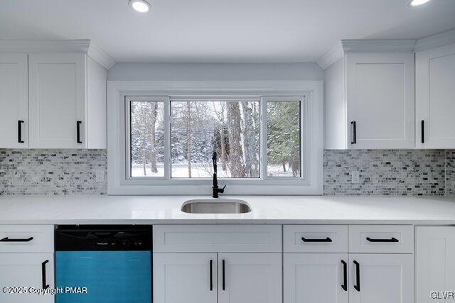 kitchen with dishwashing machine, sink, backsplash, and white cabinets