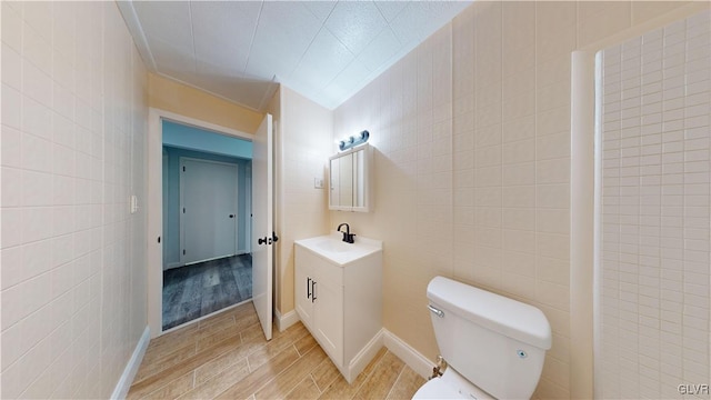 bathroom featuring vanity, toilet, and tile walls