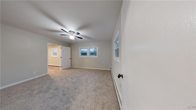 carpeted spare room with a baseboard radiator and ceiling fan