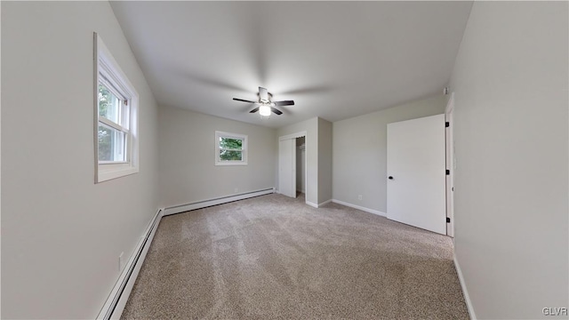 carpeted spare room with ceiling fan and a baseboard heating unit