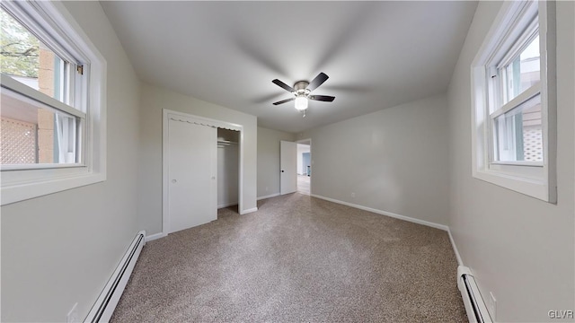 unfurnished bedroom featuring multiple windows, a baseboard heating unit, and ceiling fan