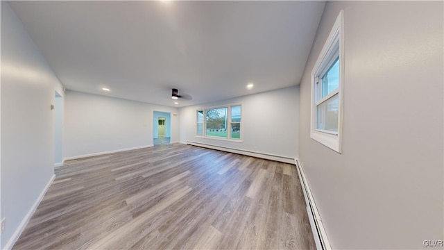 empty room featuring a baseboard heating unit and light hardwood / wood-style floors