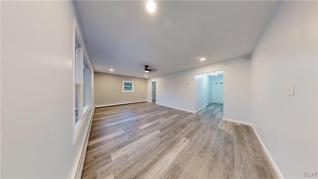 spare room featuring baseboard heating and light wood-type flooring