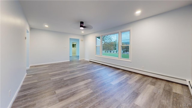 spare room with a baseboard heating unit and light wood-type flooring