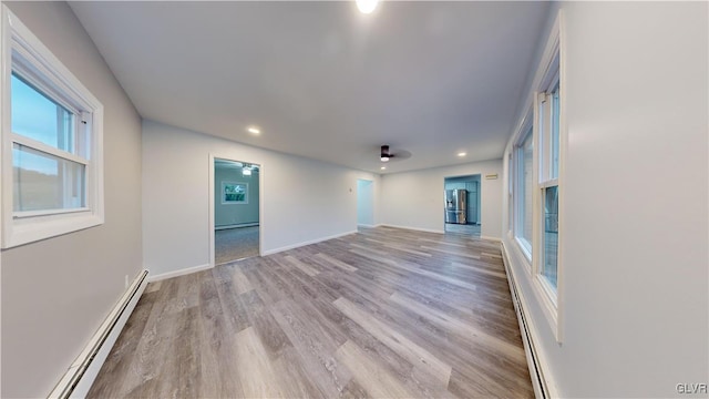 unfurnished living room with a baseboard radiator and light wood-type flooring